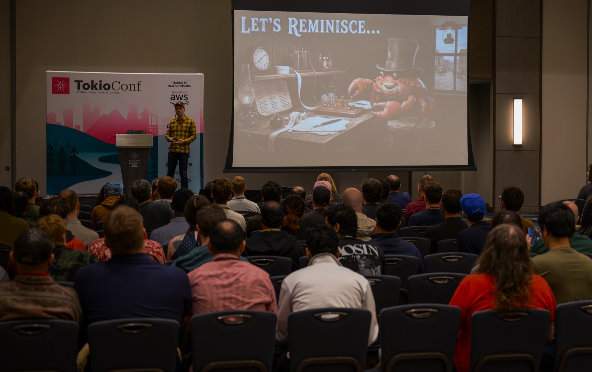 A speaker on stage at TokioConf 2026 in front of a full room